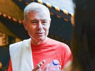 Water bottle and towel on a bench in gym.